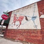 Union, OR 22 A mural of a horse with a map behind it is painted on a red brick wall at the corner of Main Street and Union. Nearby are a stop sign, a no parking sign, and a street sign reading “Espresso.”.