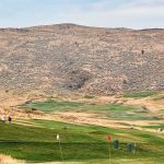 Union, OR 17 A wide view of a golf course with green fairways and flags, set against a backdrop of dry, rolling hills under a partly cloudy sky.